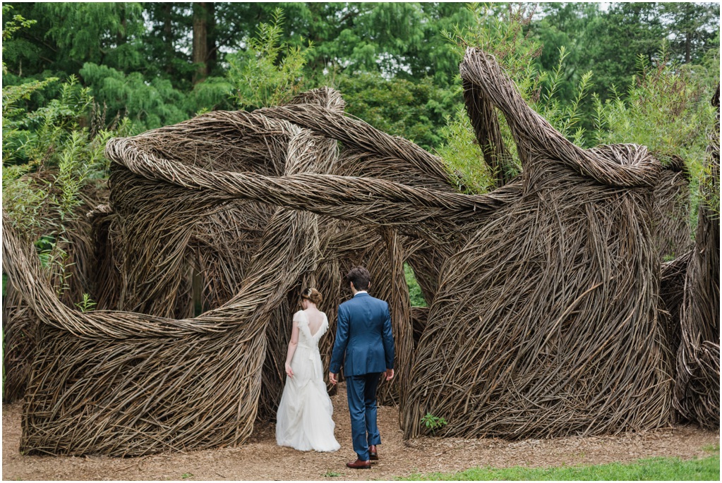 The couple walks towards a wooden sculpture.
