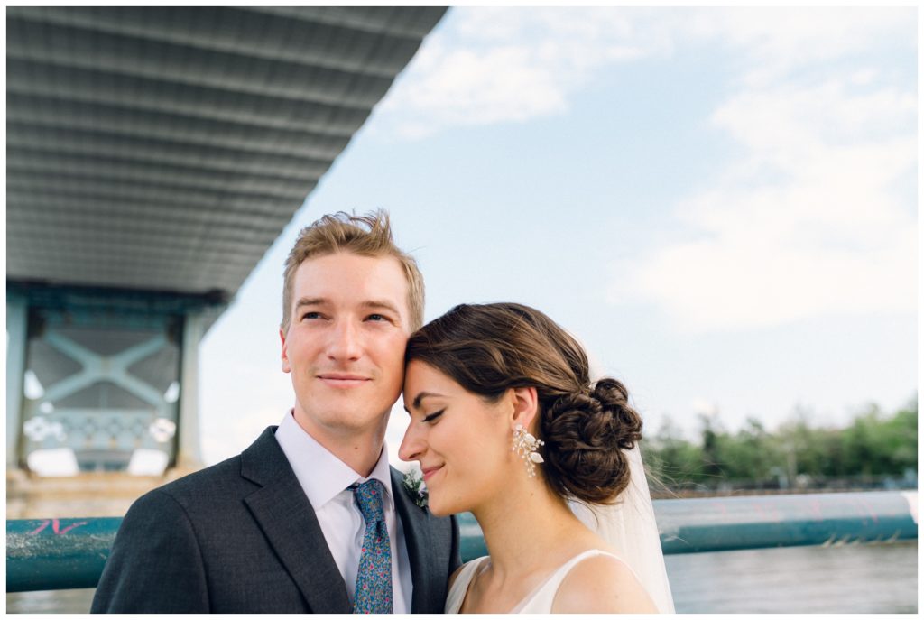 The couple stands beneath the Benjamin Franklin Bridge before their Power Plant Productions wedding
