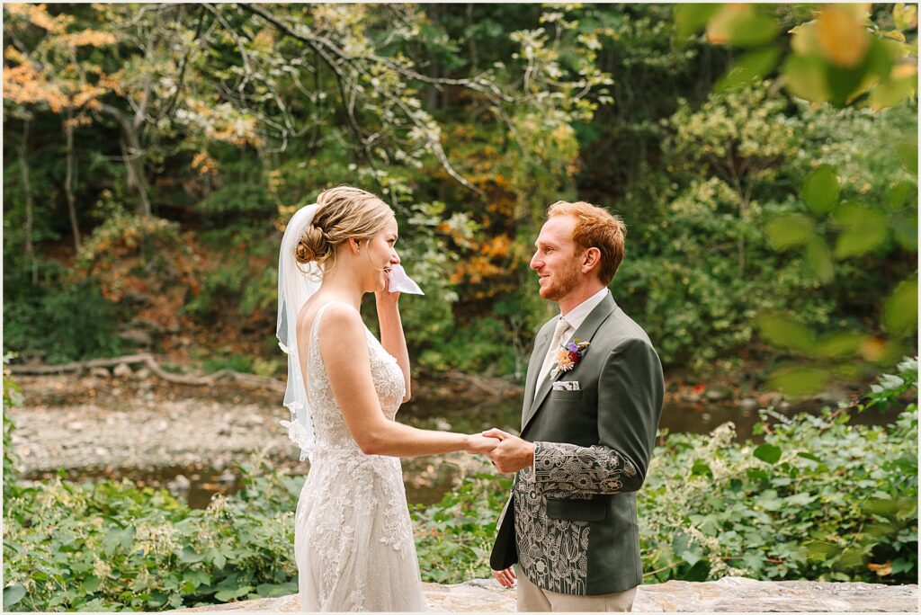 A bride wipes away tears during a first look at Wissahickon Valley Park.