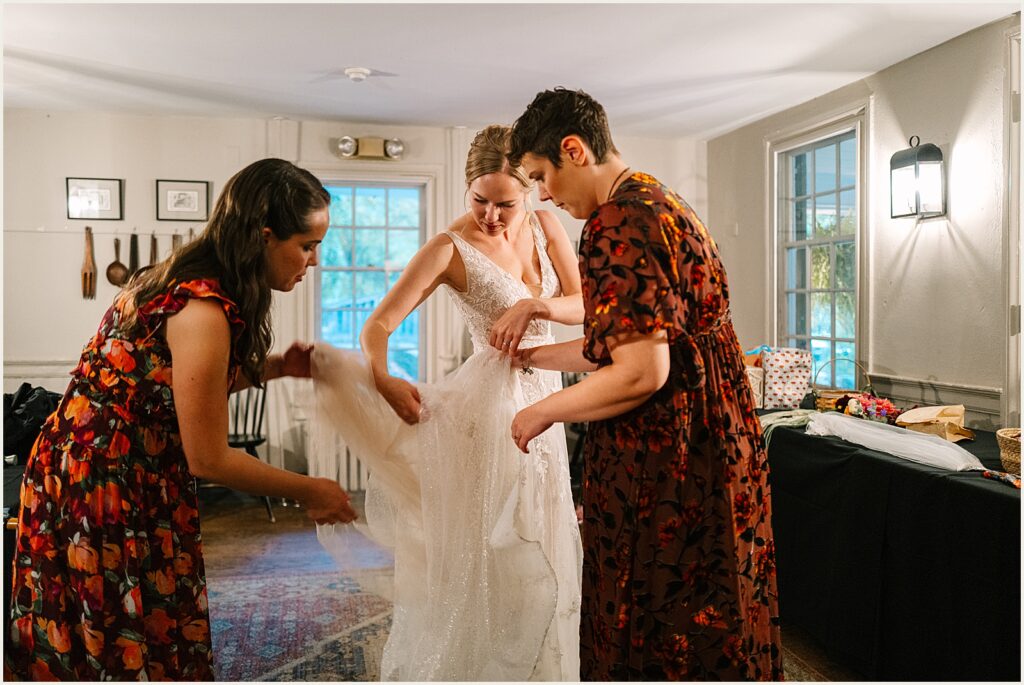A bride's friends help her bustle her dress.