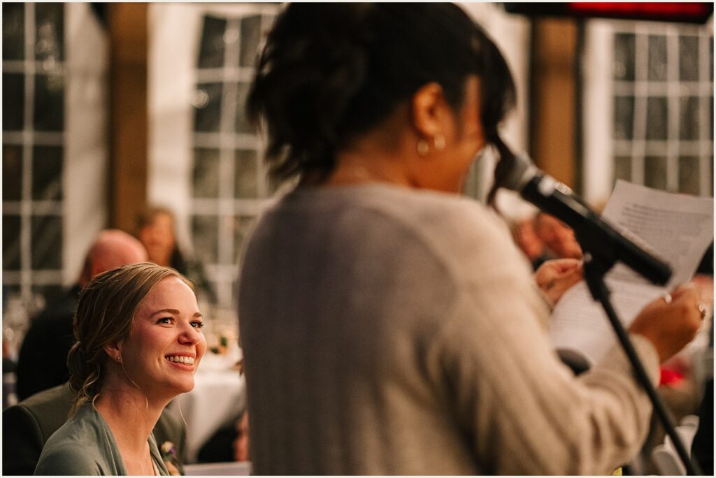 A bride smiles during a wedding toast.