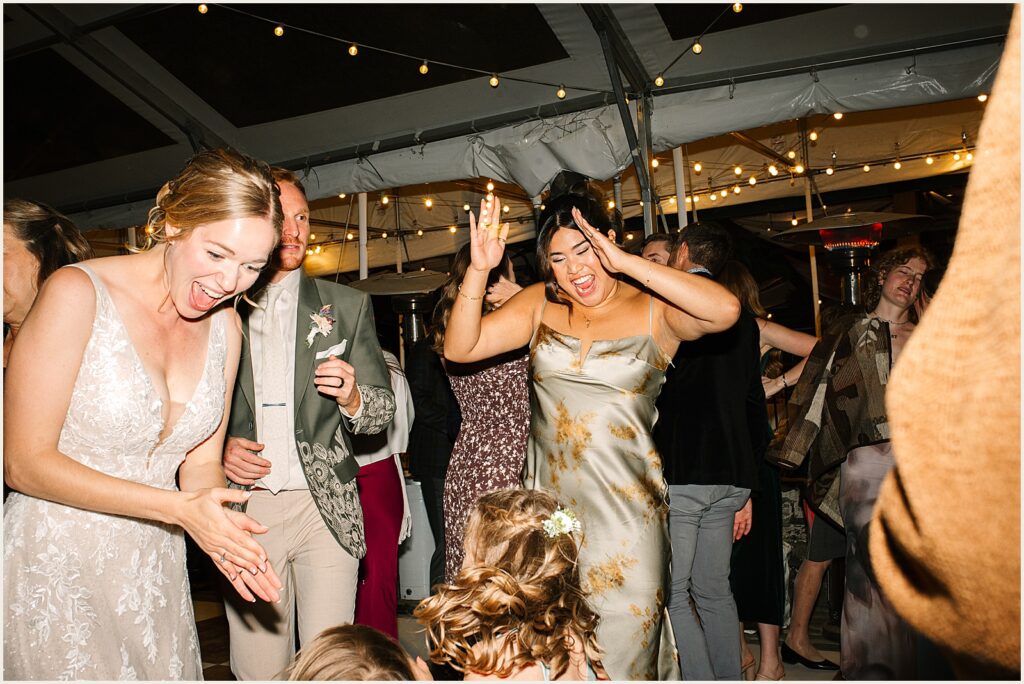 A bride dances with friends at a reception.
