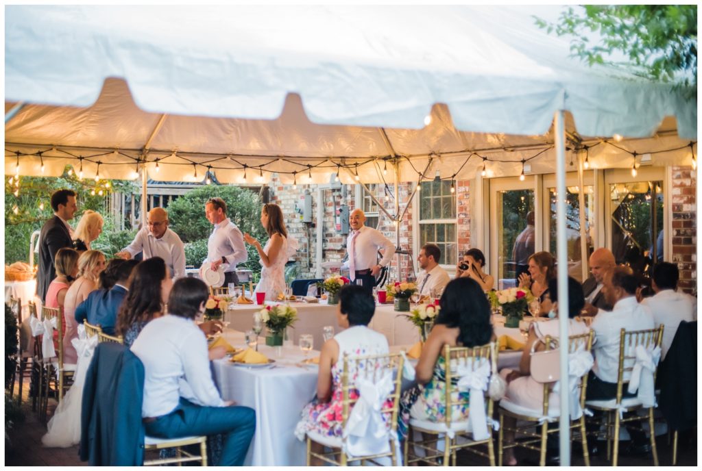 Guests sit to dinner in a tent ideas for backyard wedding