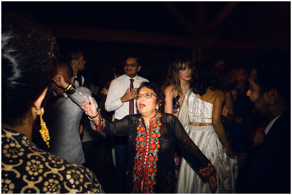 A wedding guest dances in a black and red dress.