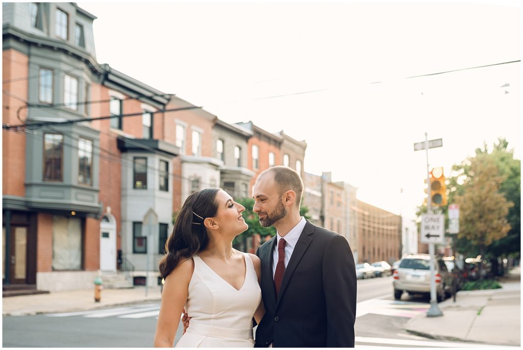 A Philadelphia wedding couple smiles on a street corner.