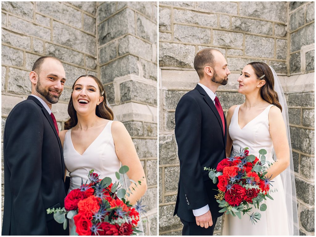 The couple poses against the gray stone exterior of their wedding venue with the bride's bouquet.