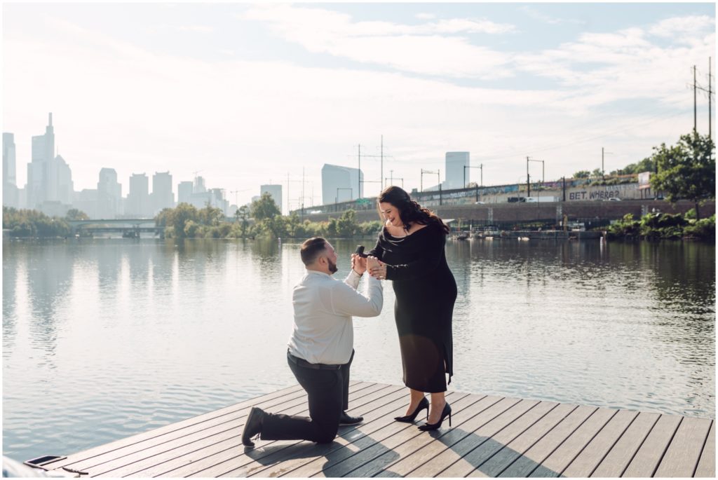 A man decides where to propose in Philadelphia at Boathouse Row on a dock.