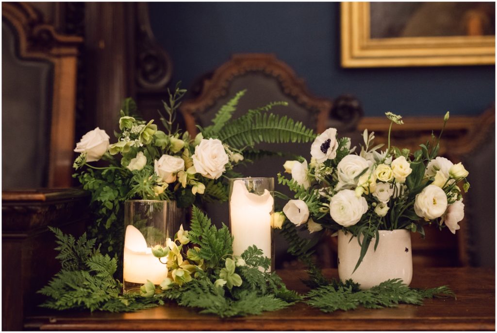Candles sit between white floral arrangements on a wedding tablescape.