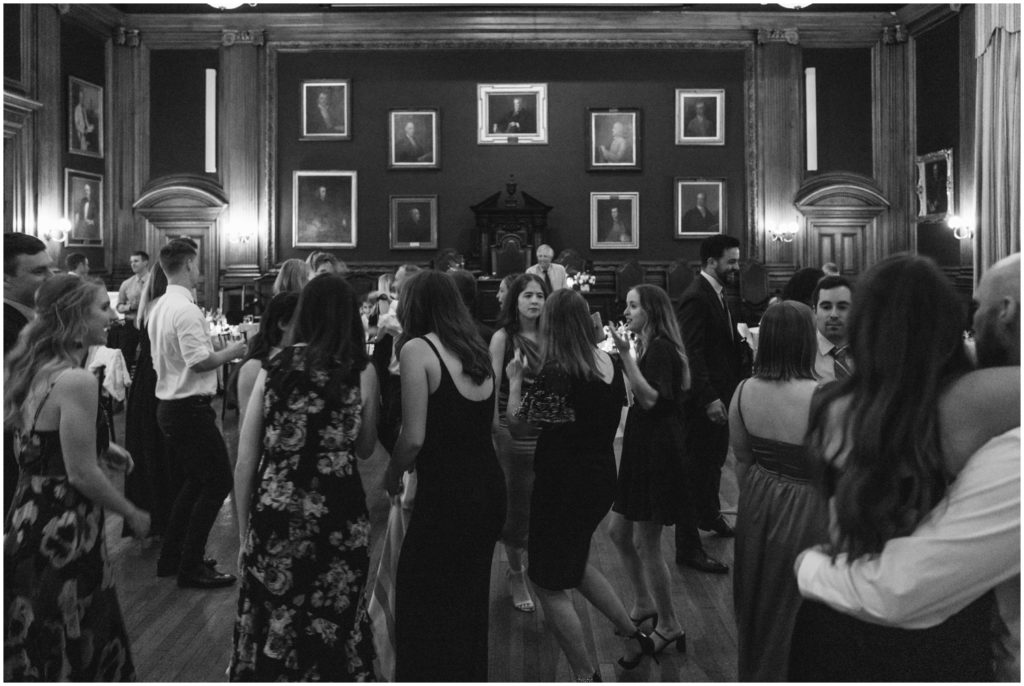 Wedding guests dance in front of a wall of portrait paintings.