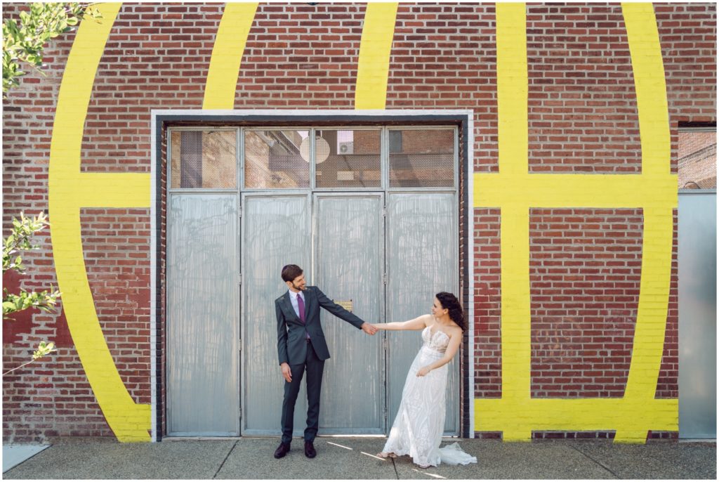 A bride and groom pose in front of a loading dock door.