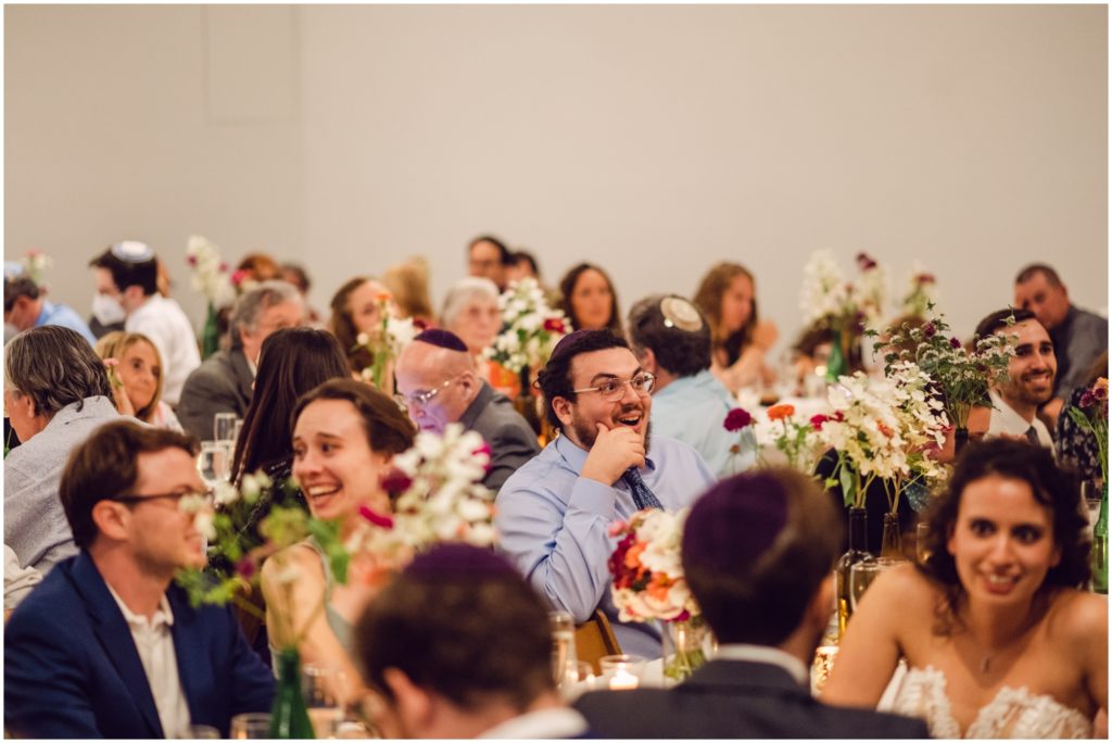 Guests laugh at wedding speeches during dinner.