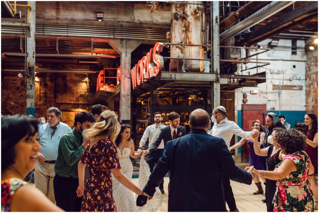 Wedding guests dance in a circle during a Globe Dye Works wedding reception.