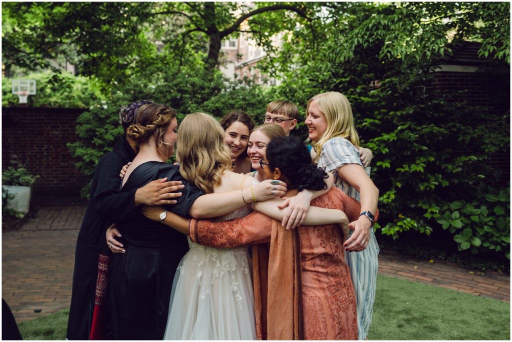 A bride's friends surround her with hugs.