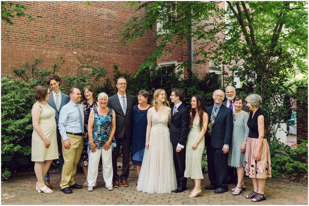 Family members stand in a line for family portraits against a brick wall.