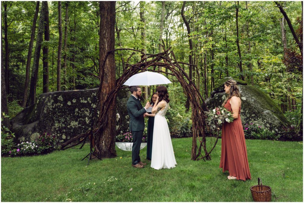 A couple exchanges vows under an arbor.