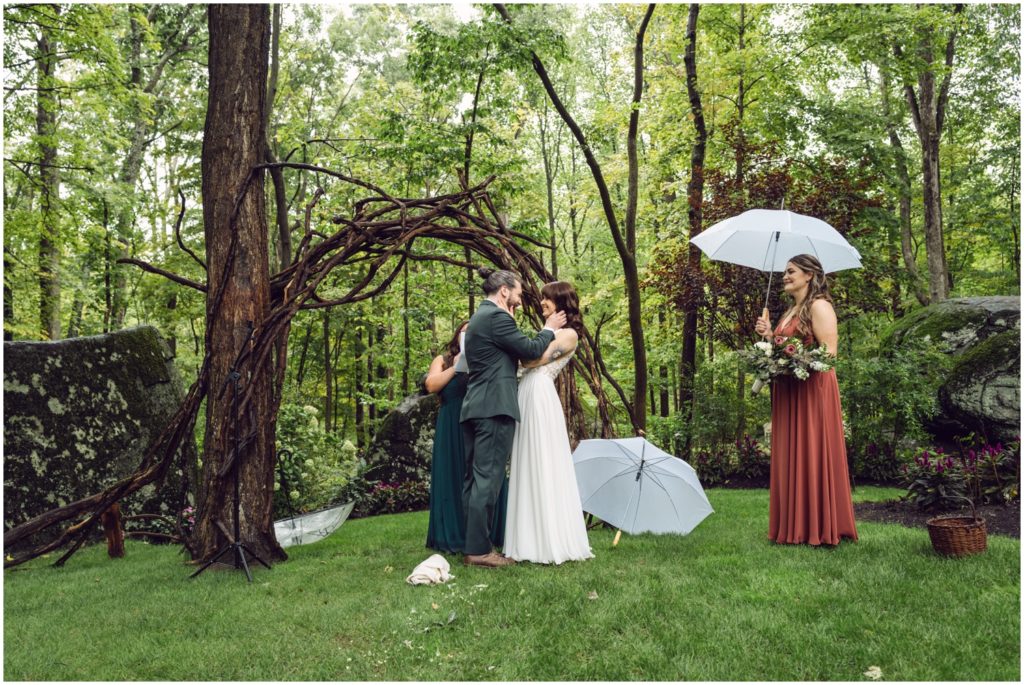 The groom drops his umbrella and embraces the bride in the rain.