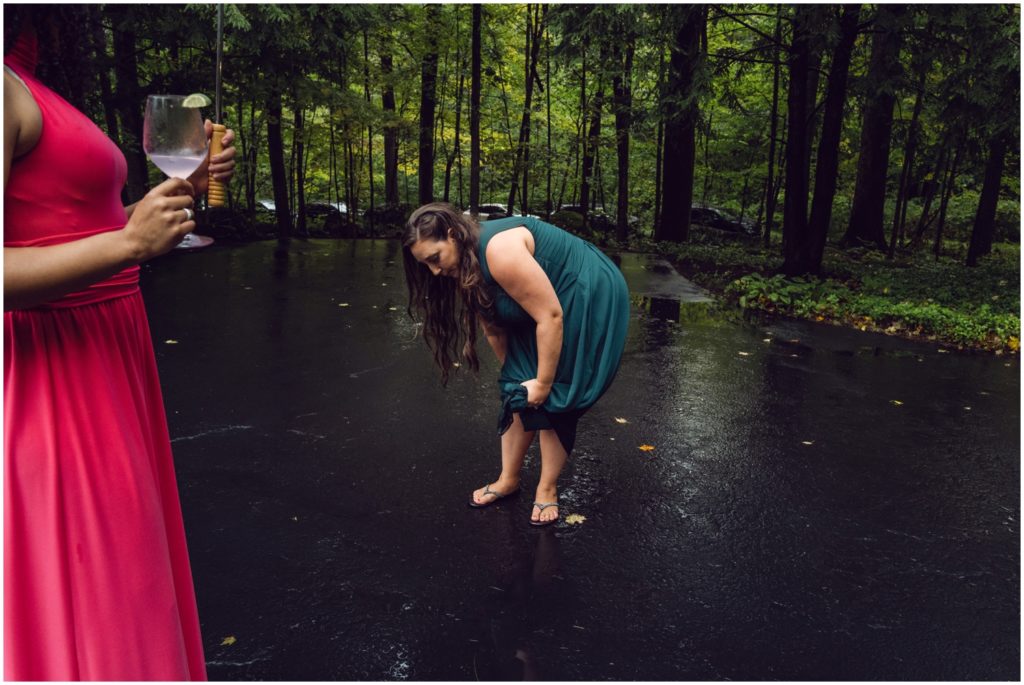 A wedding guest rings rain water out of her skirt.