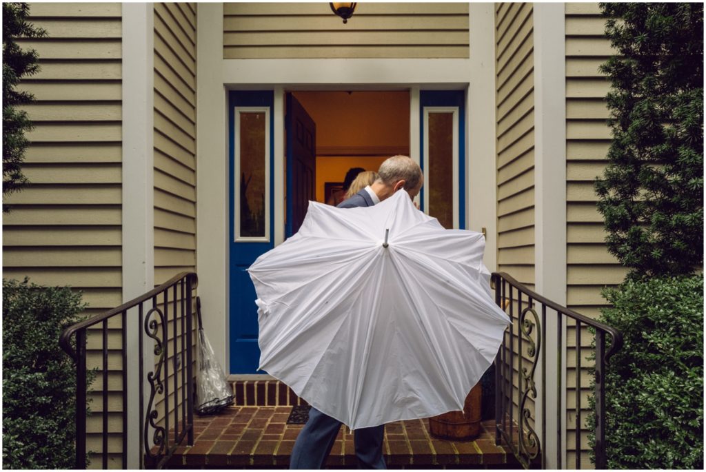 Guests close white umbrellas as they enter the house.
