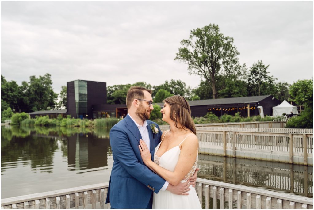 A groom puts his arms around a bride's waist with the Philadelphia Discovery Center int eh background.