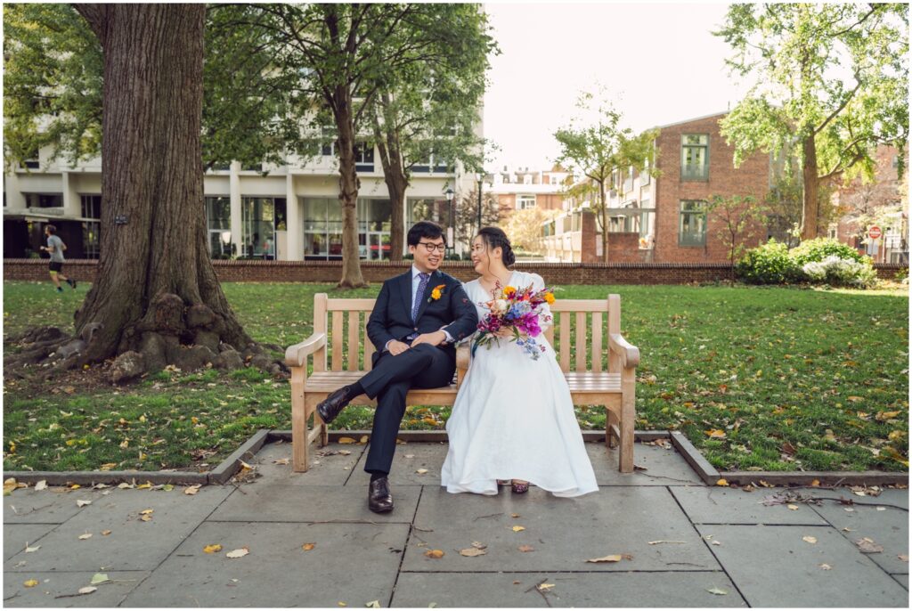 A bride and groom pose on a bench for Philadelphia wedding photos.