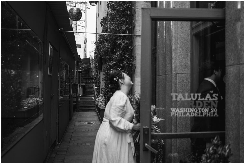 A bride laughs as she opens a restaurant door.