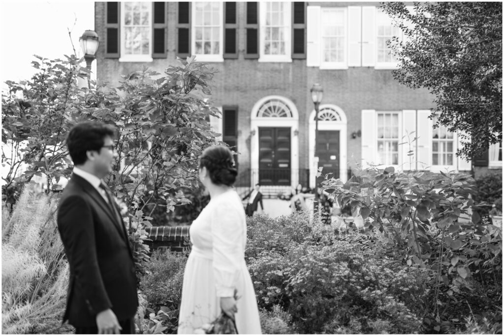A bride and groom look at a historic house in a Philadelphia park.