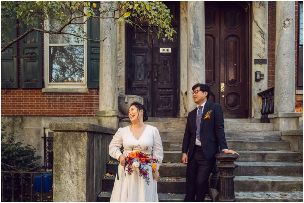 A bride and groom pose on the stoop of a Philadelphia row home.