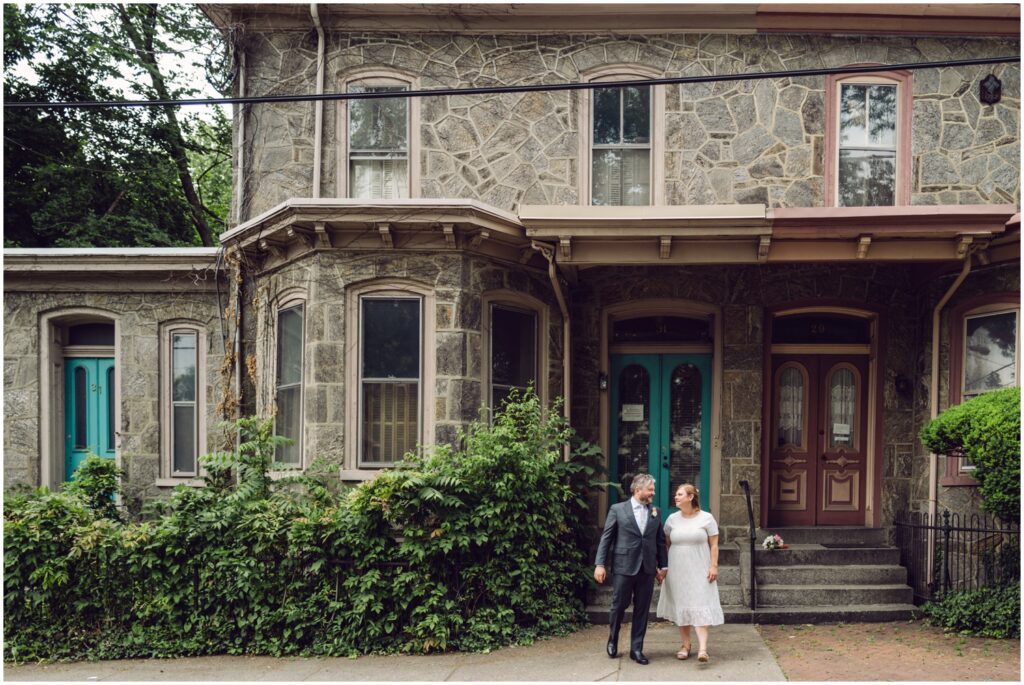 A bride and groom pose in front of a Philadelphia row home.