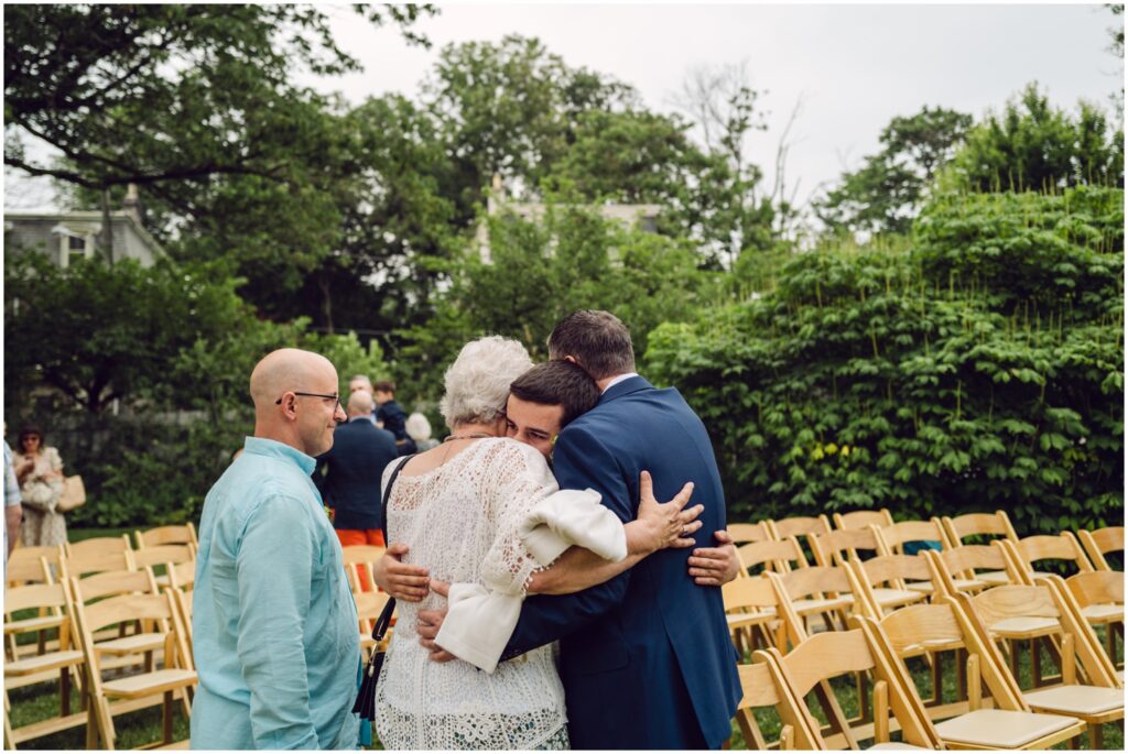 Family members embrace after an outdoor wedding ceremony.