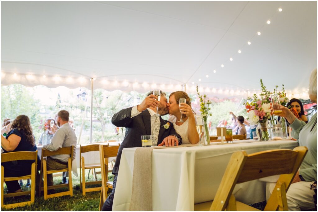 A bride and groom raise their glasses and kiss during a wedding toast.