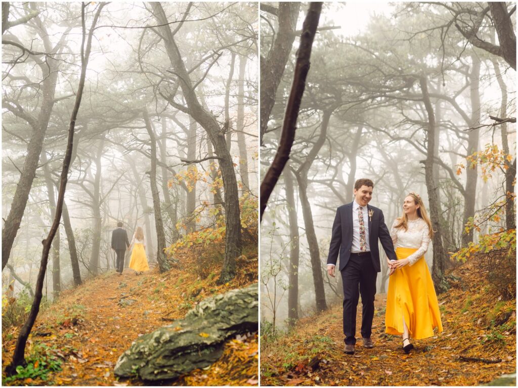 A bride and groom hold hands and walk through a misty forest.