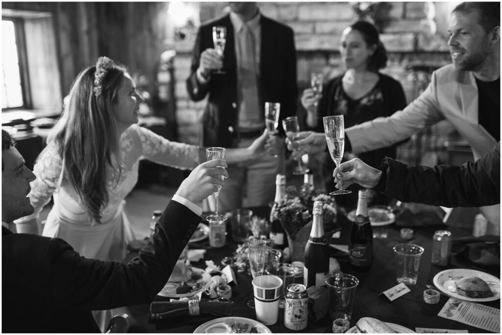 A bride and wedding guests clink glasses after a toast.