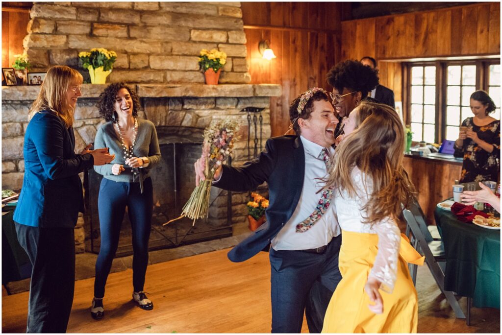A bride and groom dance surrounded by guests.