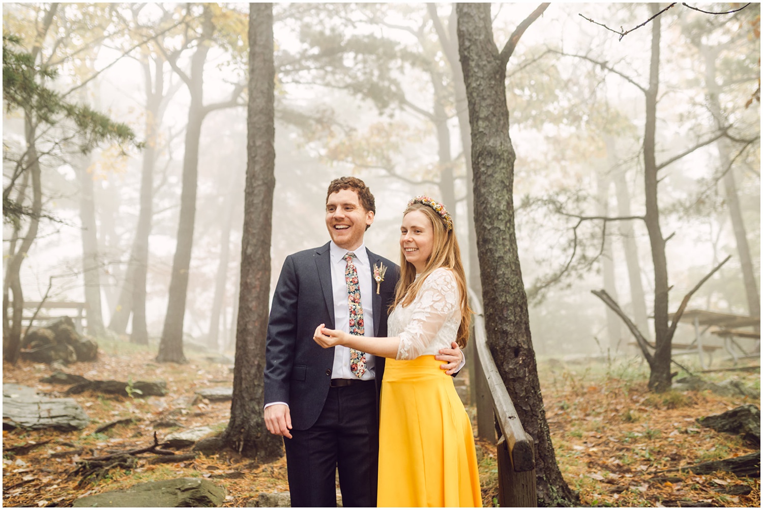 A bride and groom stand smiling in the woods after their Quaker wedding.
