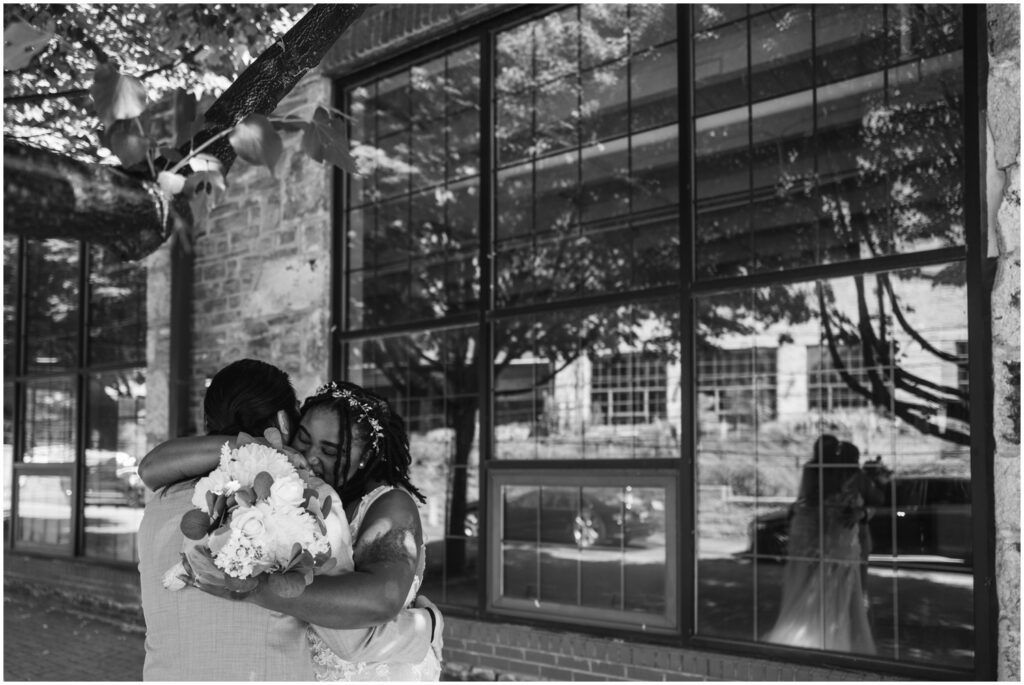 A bride and groom's reflection shows them embracing.