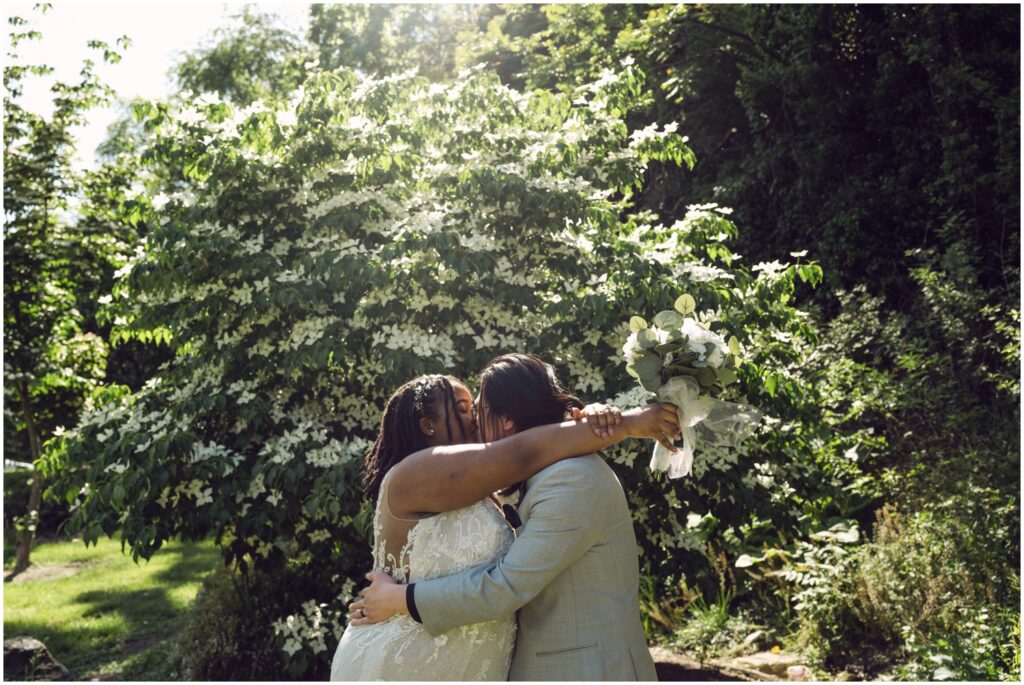 A bride and groom kiss in front of a flowering tree at their Philadelphia elopement.