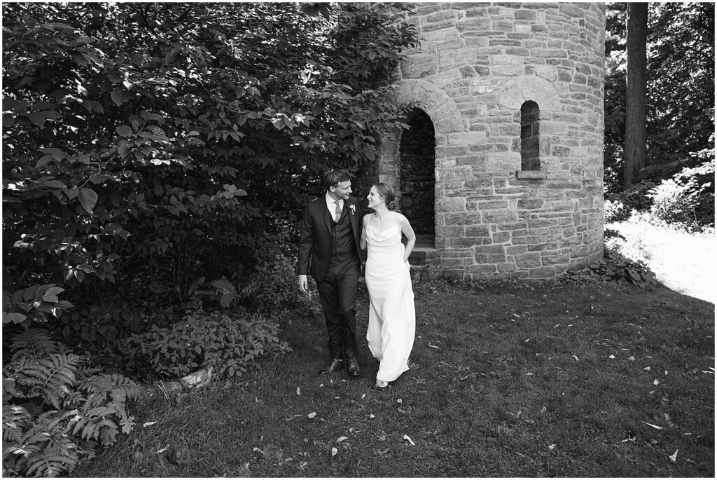 A bride and groom walk along a garden path towards a Philadelphia wedding photographer.