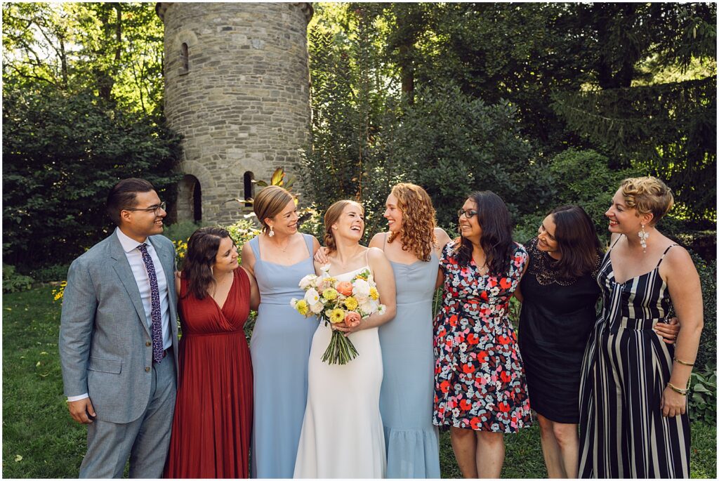 A bride poses with friends in front of a tower in the Duke Sculpture Garden.