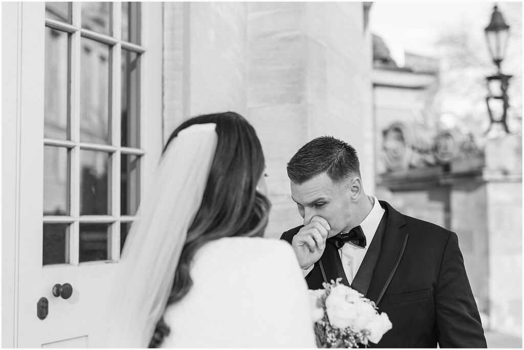 A groom wipes away a tear during the first look at a winter wedding in Philadelphia.