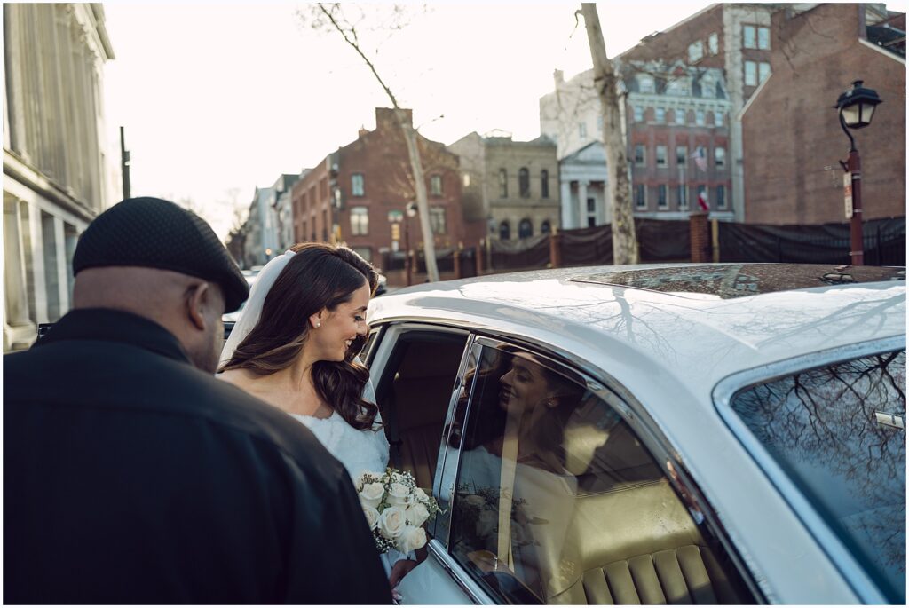 A driver opens the door of a hired car for a bride on a Philadelphia street.