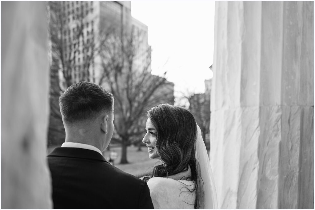 A bride smiles at a groom in a black and white wedding photo.