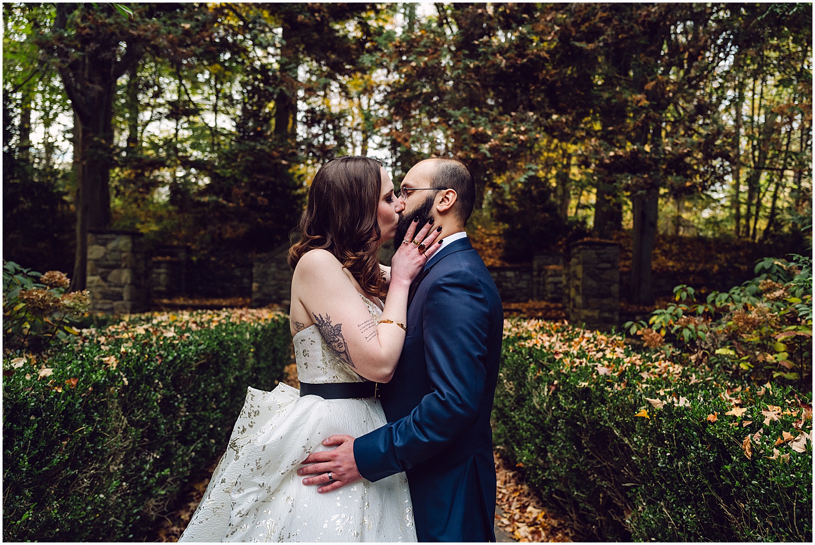 A bride and groom kiss on a garden path at a Philadelphia wedding venue.
