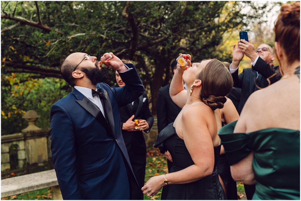 A groom takes shots with wedding guests.