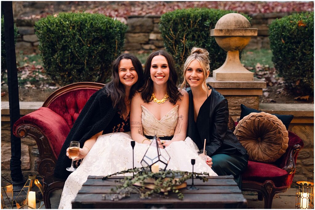 A bride sits between two friends in a conversation pit.
