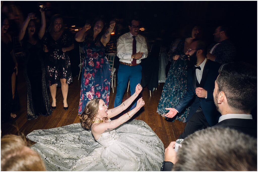 A bride dances in the middle of a circle of wedding guests.