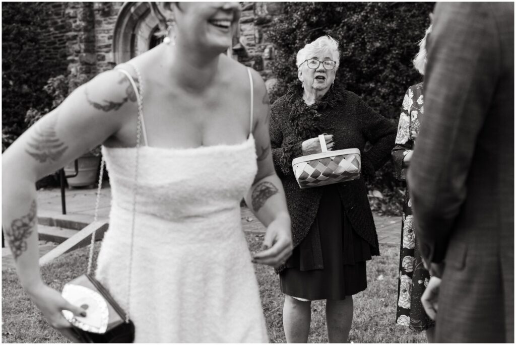 A bride laughs and adjusts her purse after a wedding ceremony.