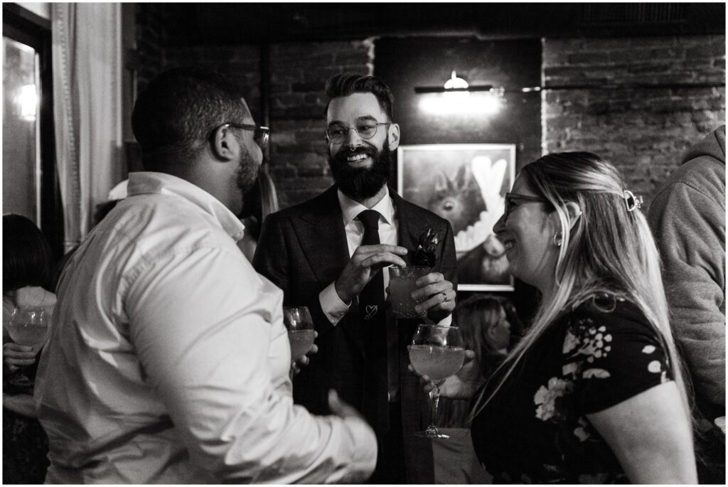 A groom drinks cocktails with wedding guests at a Philadelphia micro wedding.