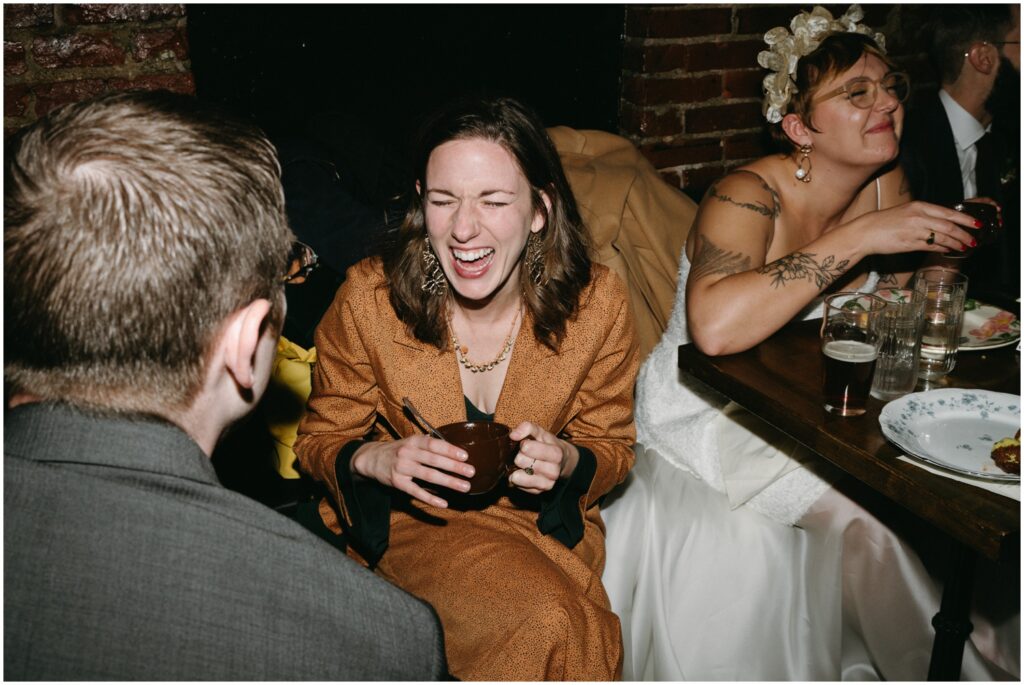 Wedding guests laugh over cocktails during a restaurant wedding.