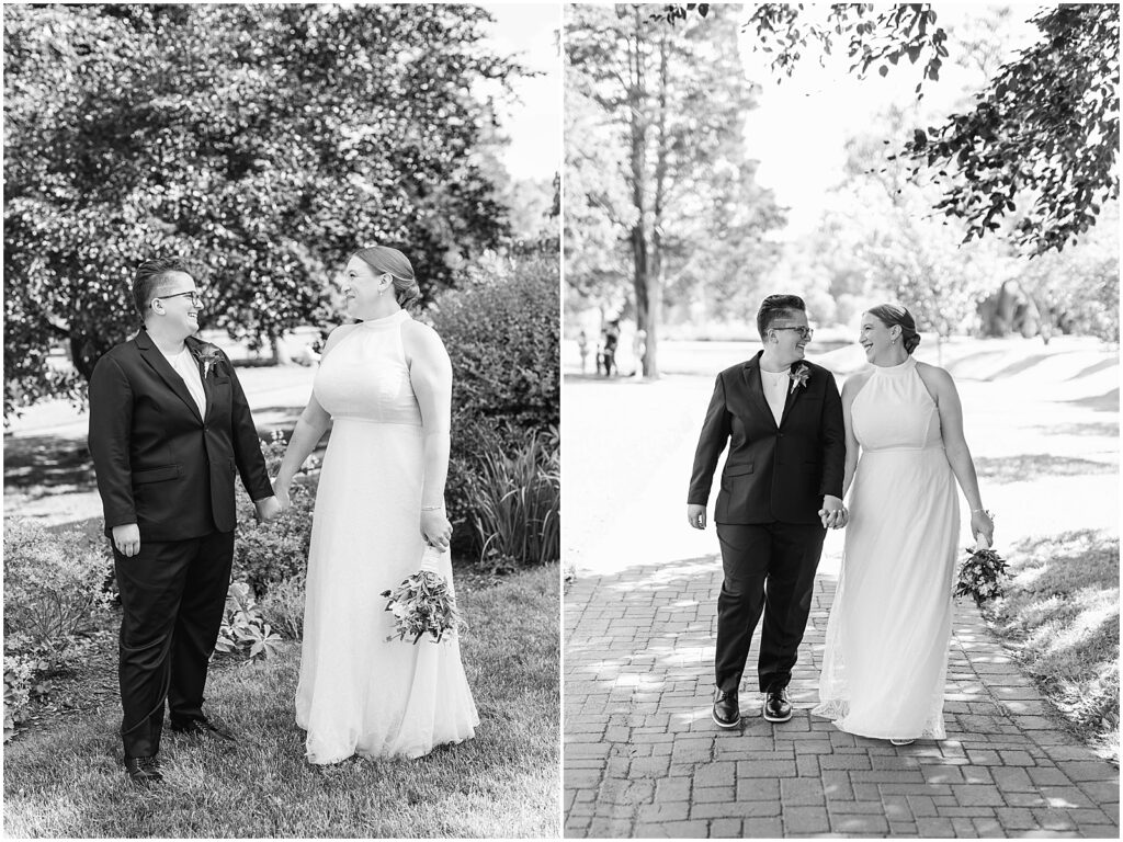 Two brides hold hands walking down a shady path in a park.