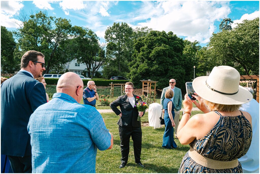 A woman in a wedding suit poses for her father to take a picture.